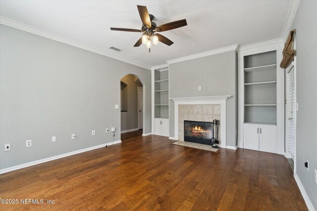 unfurnished living room with a fireplace, visible vents, built in features, baseboards, and hardwood / wood-style floors