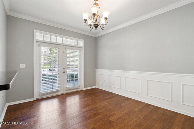 unfurnished dining area featuring ornamental molding, dark wood-style flooring, french doors, and an inviting chandelier