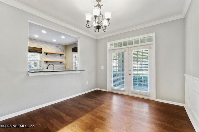 empty room with baseboards, hardwood / wood-style flooring, ornamental molding, an inviting chandelier, and french doors