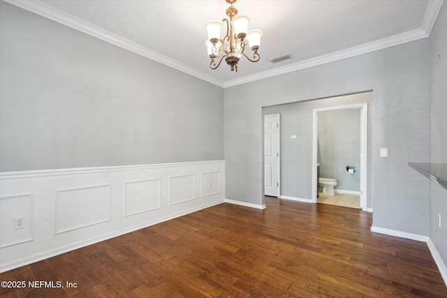 spare room with hardwood / wood-style flooring, visible vents, a notable chandelier, and ornamental molding