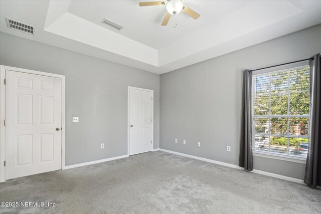 interior space with a raised ceiling, visible vents, and baseboards