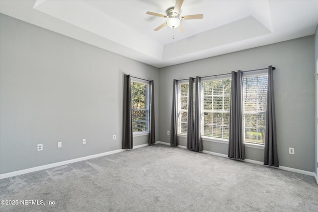 unfurnished room featuring ceiling fan, baseboards, a raised ceiling, and carpet flooring