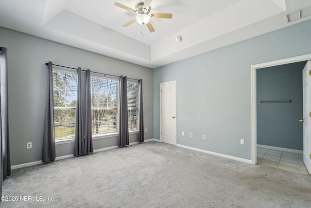 empty room with visible vents, baseboards, a ceiling fan, carpet, and a tray ceiling