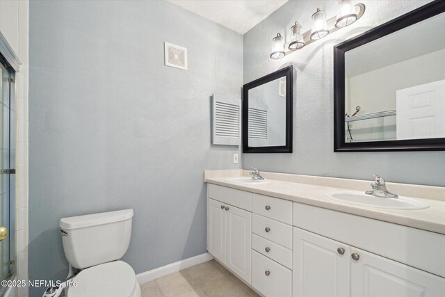 bathroom featuring a shower with door, a sink, toilet, and double vanity