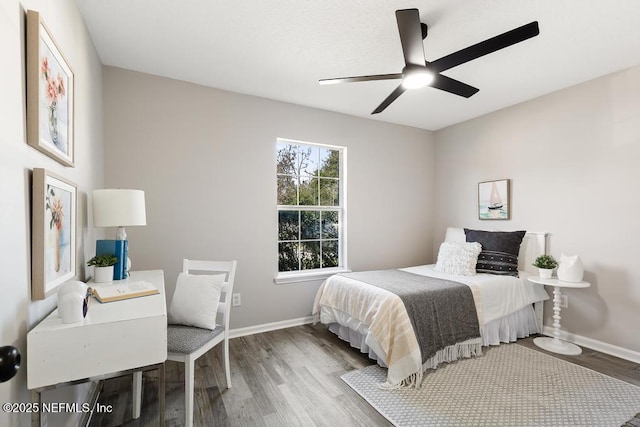 bedroom featuring a ceiling fan, baseboards, and wood finished floors