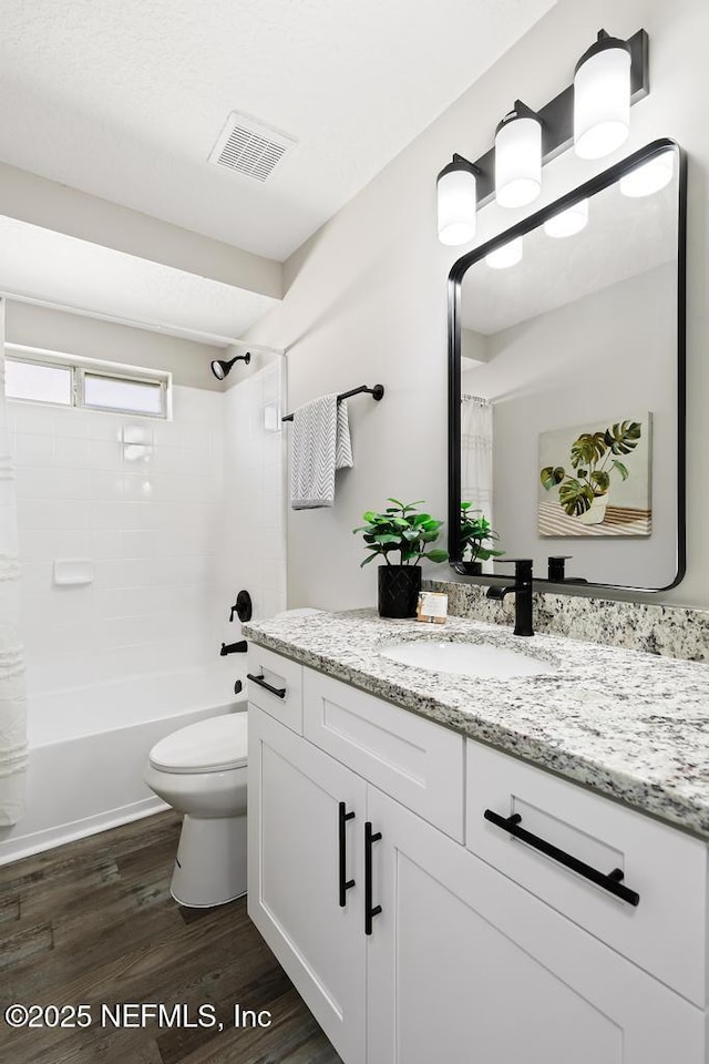 full bathroom with visible vents, shower / bathtub combination with curtain, toilet, vanity, and wood finished floors