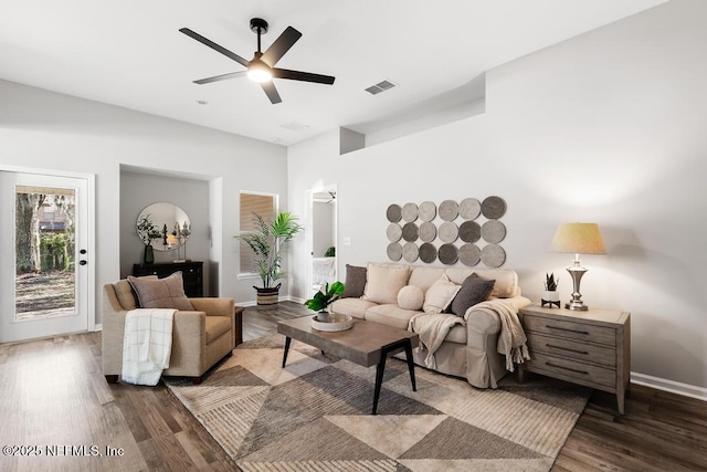 living area featuring a ceiling fan, visible vents, baseboards, and wood finished floors