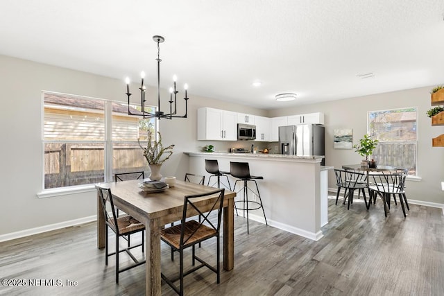 dining area featuring a notable chandelier, light wood finished floors, visible vents, and baseboards