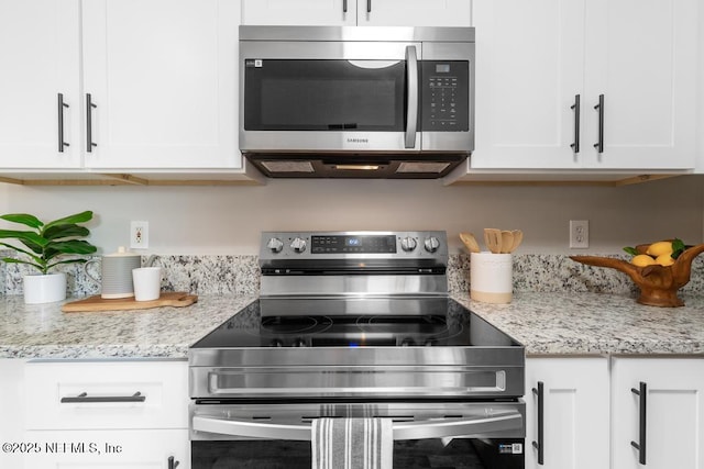 kitchen featuring appliances with stainless steel finishes, white cabinetry, and light stone counters