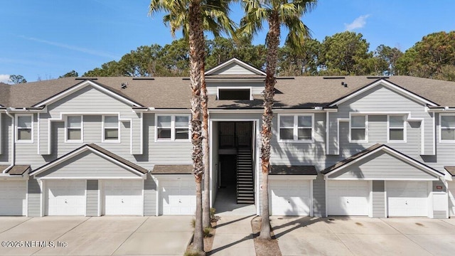 view of property with a garage, driveway, and a shingled roof