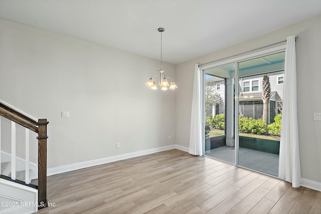 empty room featuring a chandelier, stairway, light wood-type flooring, and baseboards