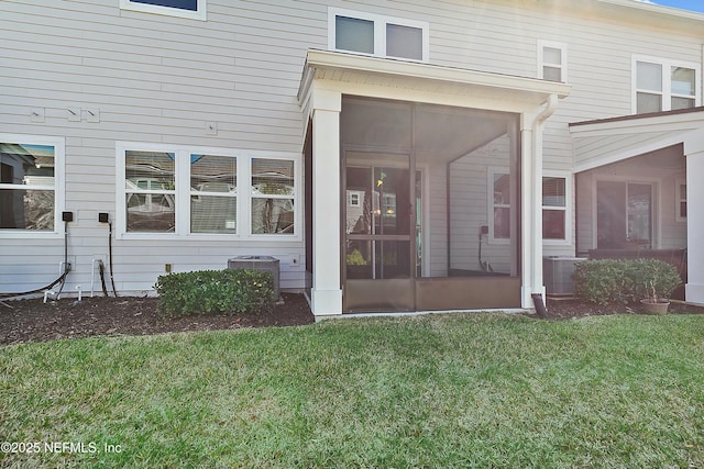 view of exterior entry featuring a lawn and central AC