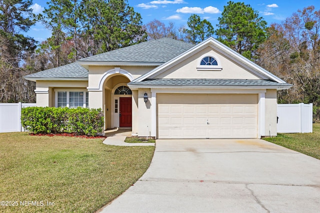 view of front of property featuring a garage, a shingled roof, concrete driveway, fence, and a front yard