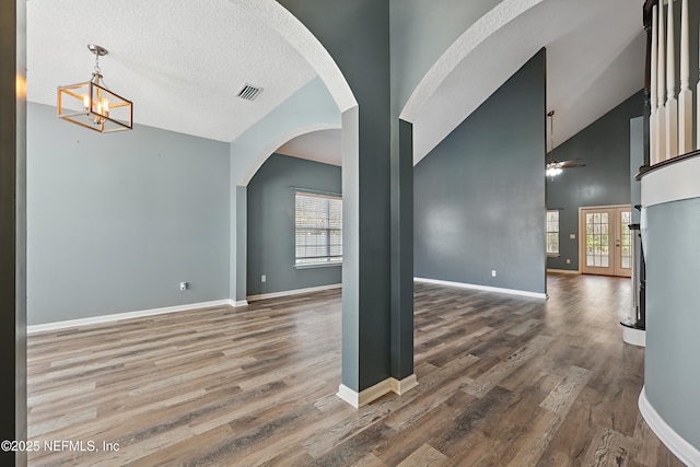 spare room with high vaulted ceiling, baseboards, visible vents, and wood finished floors