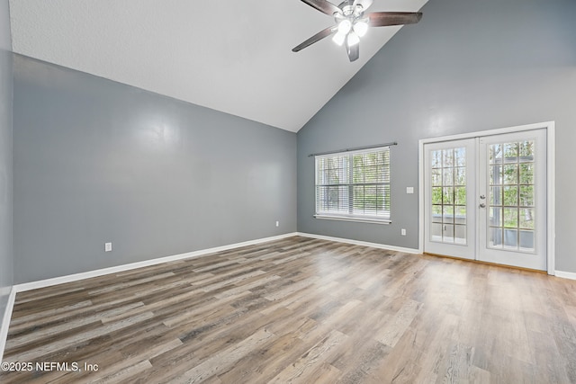 unfurnished room featuring high vaulted ceiling, baseboards, wood finished floors, and french doors