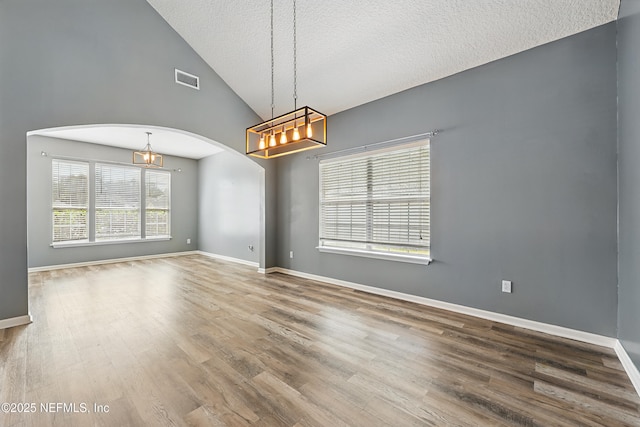 spare room featuring arched walkways, visible vents, baseboards, and wood finished floors