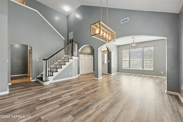 interior space featuring arched walkways, stairway, wood finished floors, and visible vents