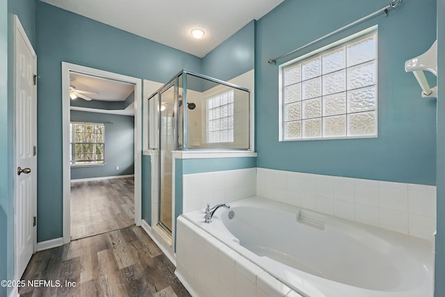 bathroom with a garden tub, a stall shower, a textured ceiling, wood finished floors, and baseboards