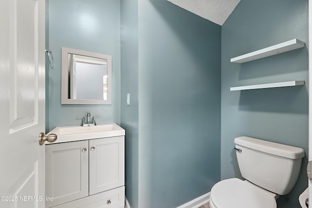 half bath featuring vanity, toilet, and baseboards