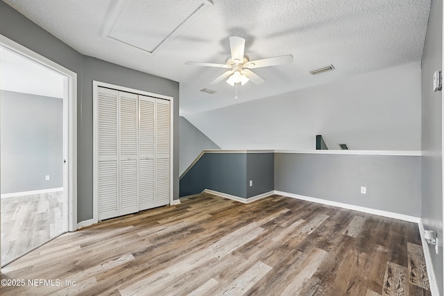 bonus room featuring a textured ceiling, wood finished floors, and visible vents