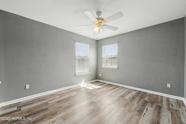 spare room with a textured ceiling, wood finished floors, a ceiling fan, and baseboards