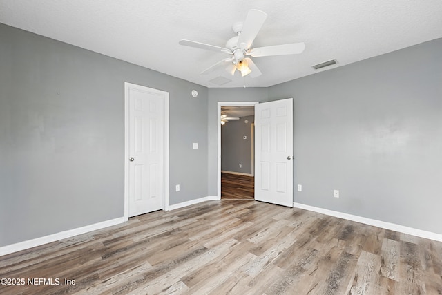 unfurnished bedroom featuring ceiling fan, wood finished floors, visible vents, and baseboards