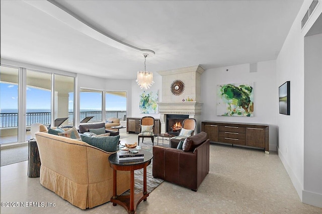 living room with a chandelier, a large fireplace, a water view, visible vents, and baseboards