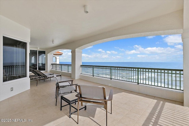 view of patio / terrace featuring a beach view, a water view, and a balcony