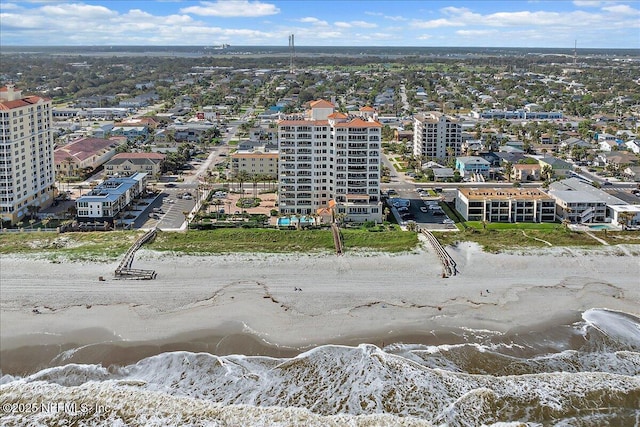 drone / aerial view featuring a view of city, a beach view, and a water view