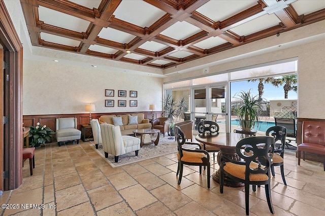 dining area featuring beam ceiling, coffered ceiling, and stone tile flooring