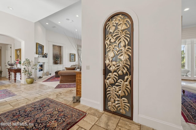 236 Deer Haven Dr, Ponte Vedra Beach, FL 32082 - entrance foyer with stone tile flooring, recessed lighting, arched walkways, a warm lit fireplace, and baseboards