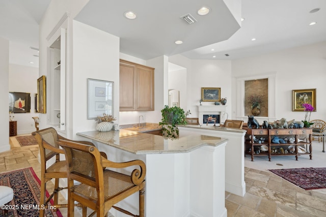 236 Deer Haven Dr, Ponte Vedra Beach, FL 32082 - kitchen featuring stone tile flooring, a peninsula, a sink, recessed lighting, and light stone counters