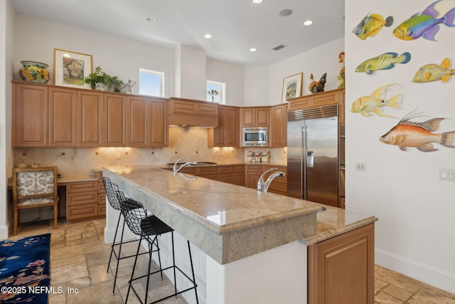 236 Deer Haven Dr, Ponte Vedra Beach, FL 32082 - kitchen featuring built in appliances, stone tile flooring, tasteful backsplash, a kitchen bar, and recessed lighting