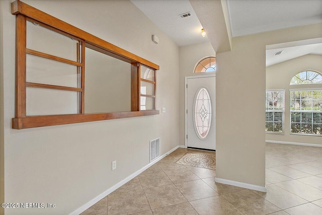 entryway featuring tile patterned flooring, visible vents, vaulted ceiling, and baseboards