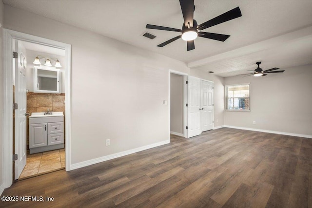 unfurnished bedroom featuring a sink, baseboards, visible vents, and wood finished floors