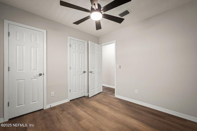 unfurnished bedroom featuring ceiling fan, wood finished floors, visible vents, and baseboards