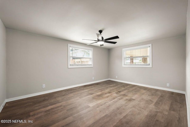 empty room with a ceiling fan, wood finished floors, a wealth of natural light, and baseboards