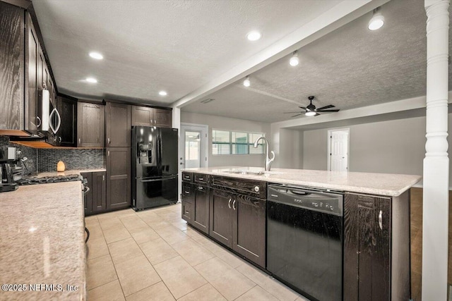 kitchen with dark brown cabinetry, a ceiling fan, a sink, black appliances, and backsplash