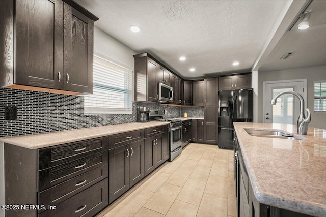 kitchen with light tile patterned floors, visible vents, a sink, stainless steel appliances, and backsplash