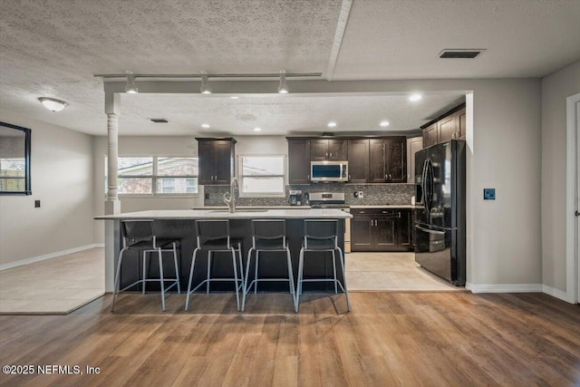 kitchen with light countertops, visible vents, backsplash, appliances with stainless steel finishes, and a sink