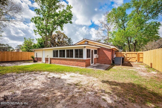 back of property featuring a gate, brick siding, a yard, and a fenced backyard