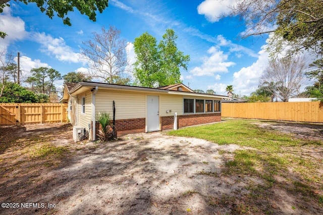 back of house with a fenced backyard, a lawn, and brick siding