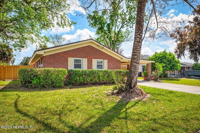 ranch-style home featuring driveway, fence, a front lawn, and brick siding