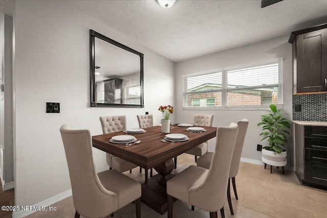 dining space featuring light tile patterned floors and baseboards