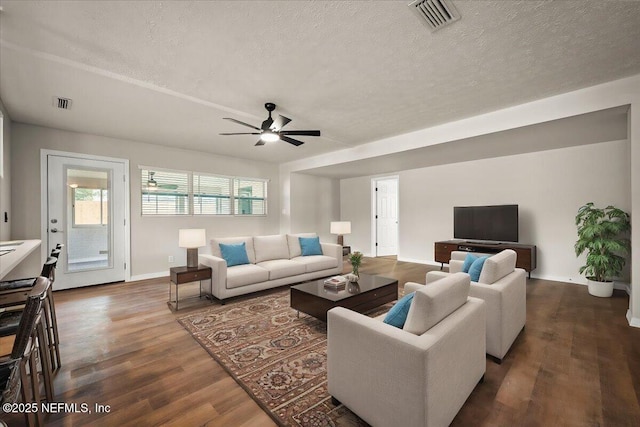 living room with a textured ceiling, dark wood-type flooring, and visible vents