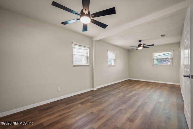 spare room with a textured ceiling, wood finished floors, a ceiling fan, visible vents, and baseboards