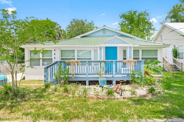 rear view of house featuring covered porch, metal roof, and a lawn