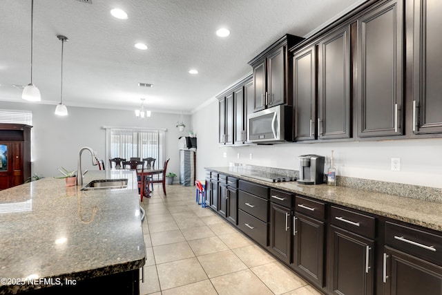 kitchen with stainless steel microwave, dark stone countertops, a textured ceiling, black electric cooktop, and a sink
