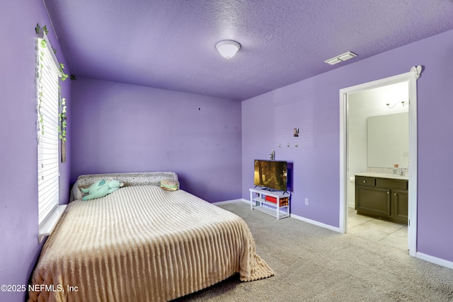 bedroom featuring visible vents, baseboards, carpet floors, ensuite bathroom, and a textured ceiling