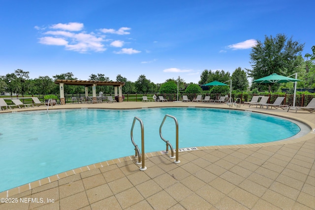 community pool with a patio area and fence